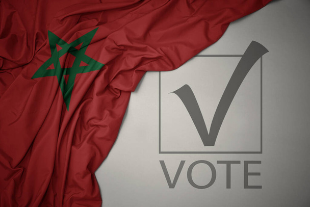 ondeando colorida bandera nacional de Marruecos sobre un fondo gris con voto de texto. concepto de elección. Ilustración 3D - Foto, imagen