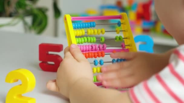 Een kleuter speelt met een abacus, leert tellen, draait de wielen van biljetten op en neer. Ontwikkeling van fijne motoriek en wiskunde - Video