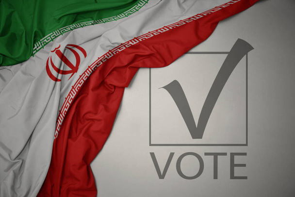 ondeando colorida bandera nacional de Irán sobre un fondo gris con voto de texto. concepto de elección. Ilustración 3D - Foto, imagen