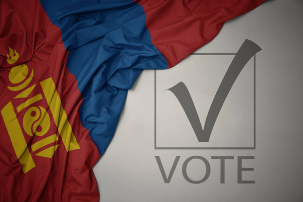 ondeando colorida bandera nacional de mongolia sobre un fondo gris con voto de texto. concepto de elección. Ilustración 3D - Foto, imagen