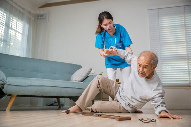 Asian older senior man falling down on lying floor and woman nurse came to help support, Disabled elderly old man patient fall down and caring young assistant at nursing home - Foto, Bild