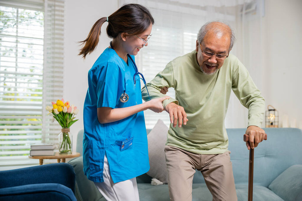 Young woman help support orthopedic patients to get up with walking cane at home, Caring nurse helping supporting senior disabled man to stand up with walking stick, International Day for the Elderly - Foto, imagen
