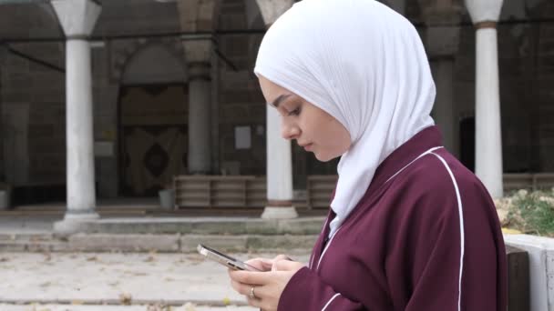 Muslim Girl Texting, chica musulmana mirando su teléfono en el patio de la mezquita, conexión en el mundo en el patio, imagen del uso de la tecnología - Metraje, vídeo