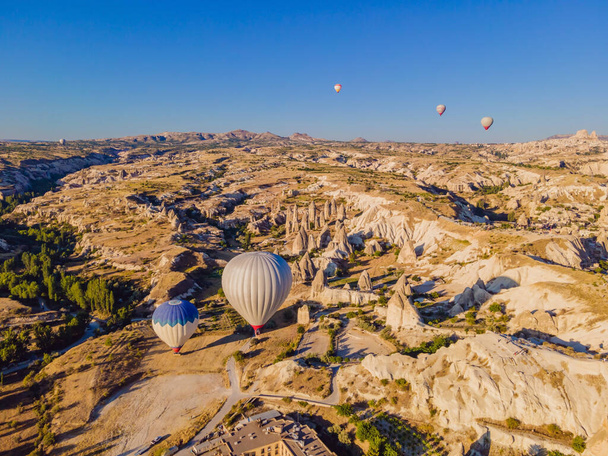 Colorful hot air balloons flying over at fairy chimneys valley in Nevsehir, Goreme, Cappadocia Turkey. Spectacular panoramic drone view of the underground city and ballooning tourism. High quality. - Photo, Image
