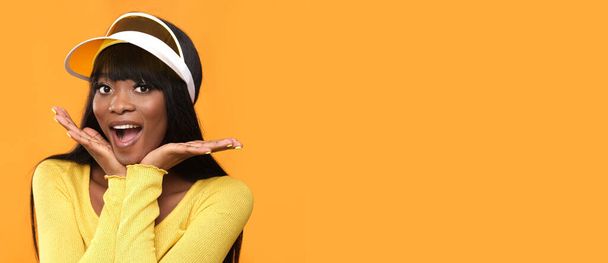 Piękna czarna skóra kobieta model pokazuje pozytywne emocje w studio fotograficznym na pomarańczowym tle. - Zdjęcie, obraz
