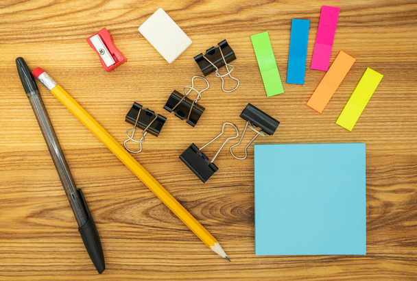 Stationery for business and education. Pencil, pen, scraper, eraser, bookmarks, paper clips and blank sticky notes, on a wooden table. - Photo, Image