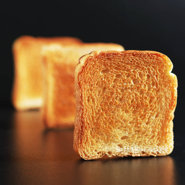 Κομμάτια μικρού φρυγανισμένου ψωμιού σε μαύρο φόντο  - Φωτογραφία, εικόνα