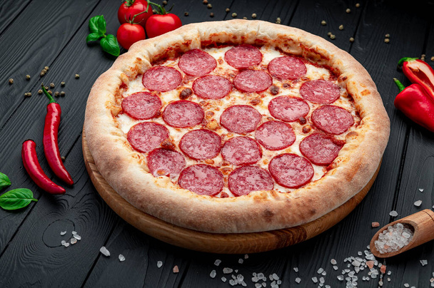 Ízletes pepperoni pizza és főzés összetevők paradicsom bazsalikom Top view of hot pepperoni pizza. - Fotó, kép