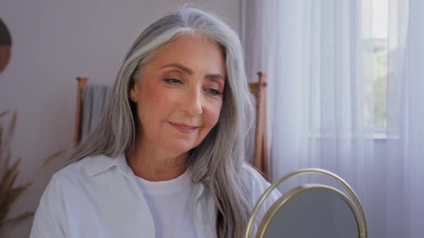 biały 60 lat w wieku starszy Dojrzałe pani stary siwe włosy 50 kobieta z lustrzanym uśmiechem patrząc na aparat piękne starzenie pomarszczony twarz anti-aging operacja podnoszenie pielęgnacji skóry nawilżające odmłodzenie - Materiał filmowy, wideo
