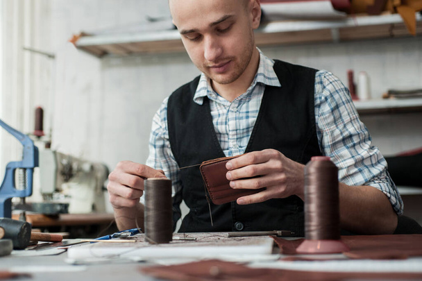 革製品の生産、バッグ、財布、クラッチの縫製。密接な接なステッチ。製品の手縫い. - 写真・画像