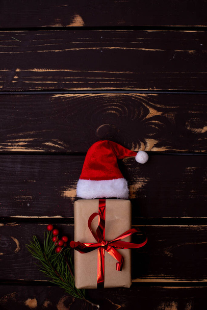 Вид зверху фото різдвяної подарункової коробки плоскої плоскої лінії, капелюха Санти та різдвяної ялини гілки на дерев'яному фоні. Різдвяний фон з пробілом для text.Copyspace. Vertical photo
. - Фото, зображення