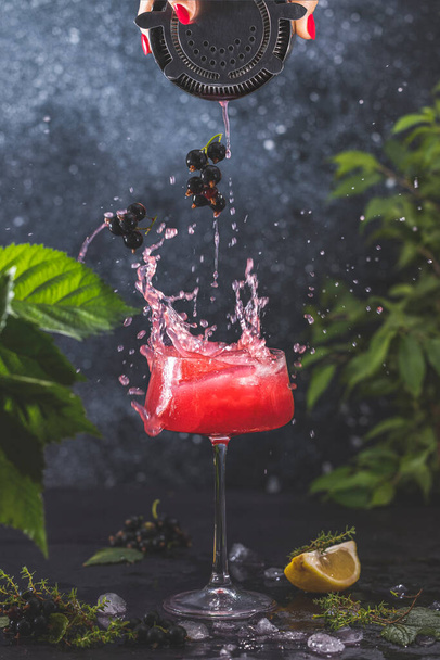 Tyylikäs lasi mustaherukka Gin hapan cocktail tai mocktaileja roiskeita ympäröivät ainesosat tummalla pöydällä pinnalla. Virkistävä juoma juomakelpoista. - Valokuva, kuva