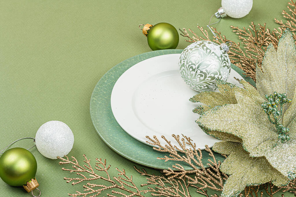 Weihnachtstisch mit leeren Keramiktellern, traditionellen Accessoires auf trendigem Hintergrund in Savannah Green. Festliches Neujahrsbesteck, flache Lage, Kopierraum - Foto, Bild