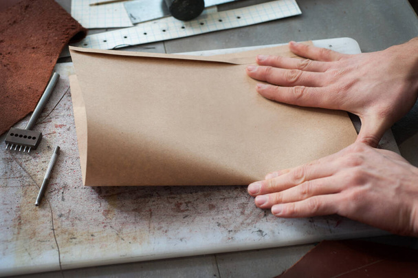 the process of assembling paper kraft bags for packaging handmade leather goods. Small business, manufactories - Fotoğraf, Görsel