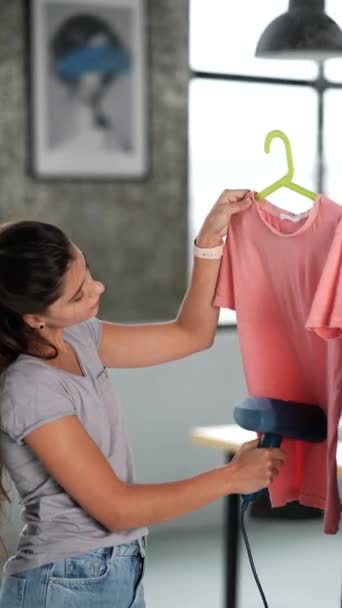 Schöne junge Hausfrau bügelt Kleidung mit einem Dampfer - Filmmaterial, Video