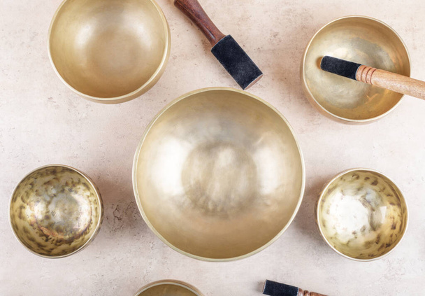 Tibetan singing bowls with stick used during mantra meditations on beige stone background, top view, flat lay. Sound healing music instruments for meditation, relaxation, yoga, massage, mental health - Photo, Image