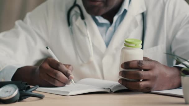 Médecin africain inconnu thérapeute cardiologue pharmacien assis à l'hôpital clinique écrire diagnostiquer recette médicale avis de rendez-vous médicament dosage de médicaments pilules comprimés de vitamines pour l'immunité - Séquence, vidéo
