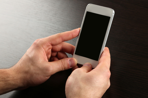 Hands holding smart mobile phone on wooden table background - Foto, Bild