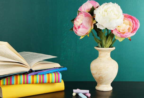 Composition on desk with books and flowers on green blackboard background - 写真・画像