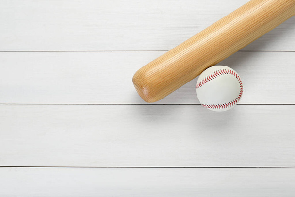 Honkbalknuppel en bal op witte houten tafel, bovenaanzicht met ruimte voor tekst. Sportuitrusting - Foto, afbeelding
