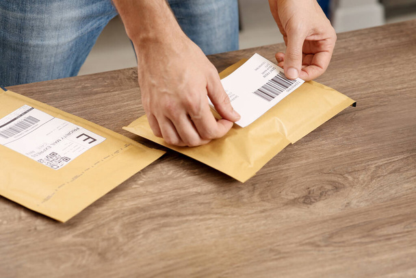 Post office worker sticking barcode on parcel at counter indoors, closeup - Fotoğraf, Görsel