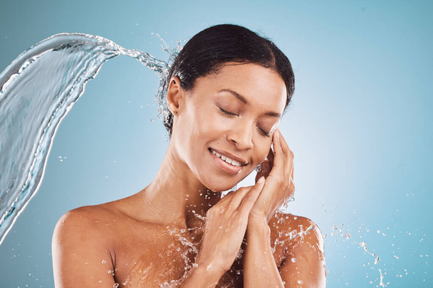 Beauty, water splash and skincare, black woman on blue background in studio. Fashion, health and wellness, clean water shower on woman with healthy mindset and luxury spa treatment in South Africa - Photo, image