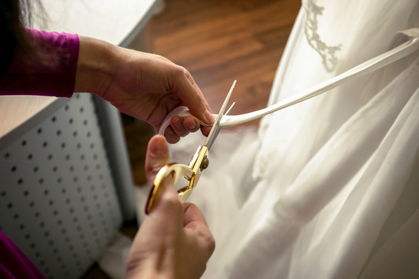 ράφτης κόβοντας την κορδέλα στο λευκό νυφικό - Φωτογραφία, εικόνα