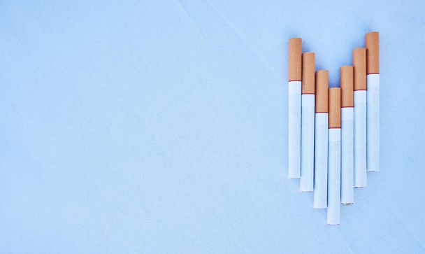 Cigarettes in a studio against a blue background mockup for cancer, toxic and addiction awareness. Cigarette, tobacco business and industry advertising for smoke, marketing and smoking market. - Foto, Imagen