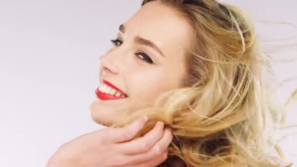 Woman, face and windy hair on studio background with makeup cosmetics, healthy hair care and facial skincare. Zoom, portrait and blonde beauty model with happy smile, balayage color and red lipstick. - Footage, Video