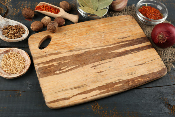 Different spices and herbs with cutting board on color wooden table background - Photo, image