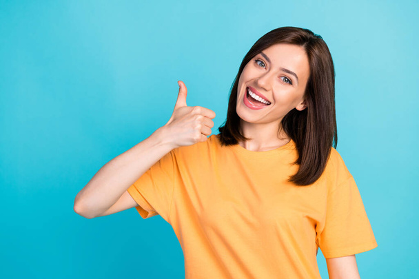 Portrait of glad pleasant cute woman with long hairstyle dressed yellow t-shirt showing thumb up isolated on blue color background. - Foto, Imagem