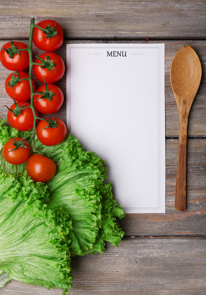 Menu sheet of paper with cherry tomatoes and lettuce on rustic wooden surface background - Valokuva, kuva