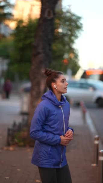 Kobieta w odzieży sportowej robi ćwiczenia rozgrzewające na ulicy miejskiej - Materiał filmowy, wideo