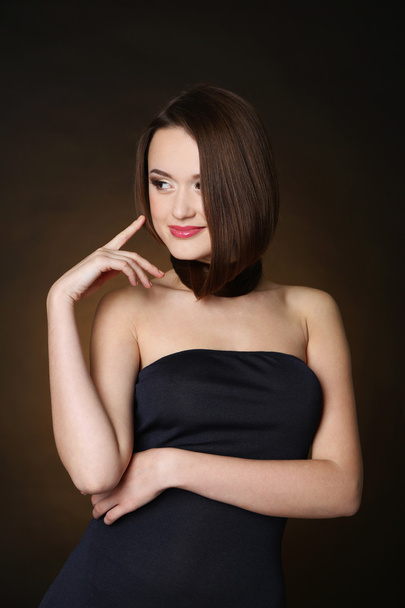 Beautiful young woman with long hair on dark brown background - Fotoğraf, Görsel