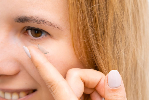 Side view of a smiling woman applying contact eye lenses. - 写真・画像