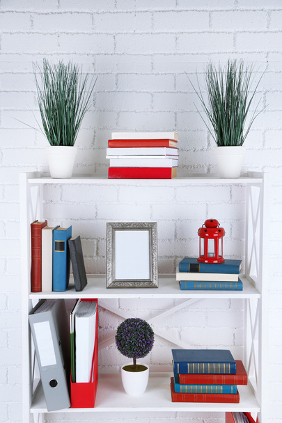 Bookshelves with books and decorative objects on brick wall background - Valokuva, kuva