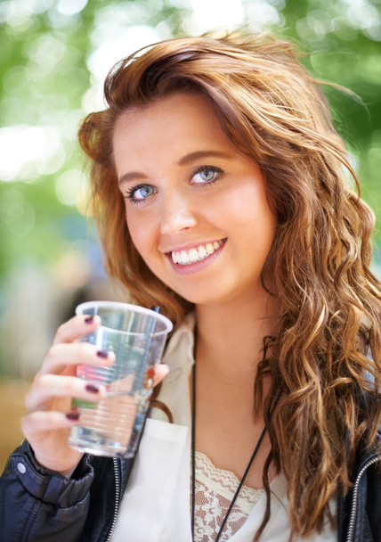Απολαμβάνω ένα αναψυκτικό. Μια νεαρή γυναίκα στέκεται έξω κρατώντας ένα ποτό - Φωτογραφία, εικόνα