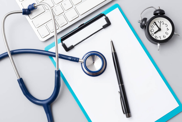Arts bureau met stethoscoop en klembord met pen, online consultatie gezondheidszorg, bovenaanzicht - Foto, afbeelding