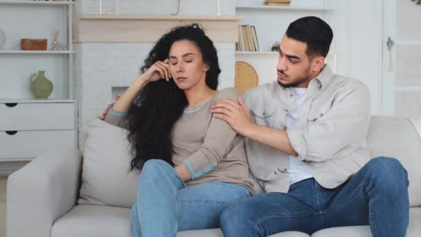 Offended upset worried desperate sad Hispanic Latino Caucasian woman wife disappointed sitting on couch caring husband Indian man consoles support apologize helping lady. Conflict married couple. High - Footage, Video
