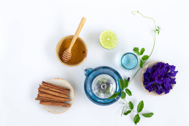 白い背景にレモンと蝶のエンドウ豆の花のお茶のトップビュー。健康飲料の概念. - 写真・画像