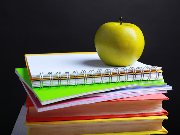 School supplies and apple on black background - Fotó, kép