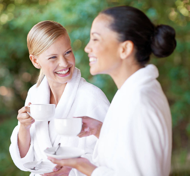 Does this herbal tea taste good or what. Two young women having coffee in their bathrobes at the day spa - Foto, imagen