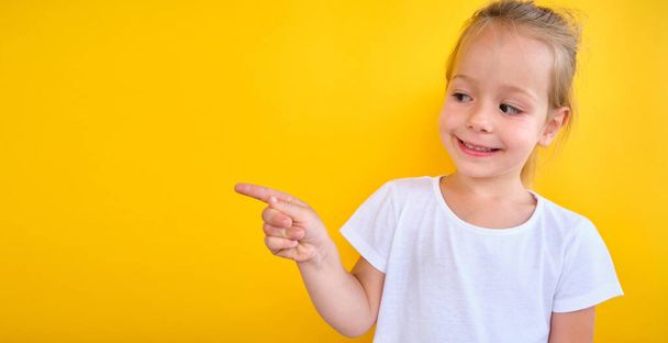 Smiling preschool girl showing , pointing at copy space for advertising text, big sale announce - Φωτογραφία, εικόνα