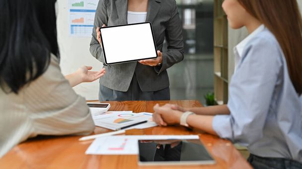 Profesjonalna azjatycka bizneswoman lub konsultant biznesowy prowadzi spotkanie i prezentuje coś na ekranie tabletu. model biały ekran tabletki. przycięty obraz - Zdjęcie, obraz