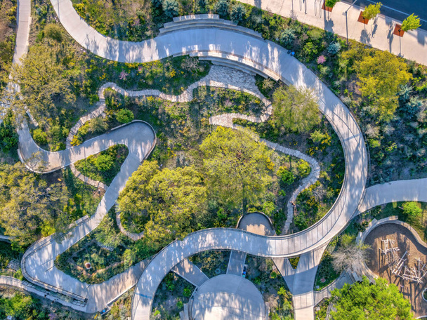 Widok z góry na abstrakcyjne betonowe chodniki w Austin w Teksasie. Widok z lotu ptaka na zielony trawnik otaczający ścieżki parku i widok na chodnik w prawym górnym rogu. - Zdjęcie, obraz