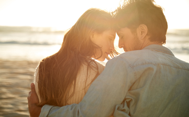 Ihr seid mein Stück Paradies. Rückansicht eines liebevollen jungen Paares, das nebeneinander am Strand sitzt - Foto, Bild