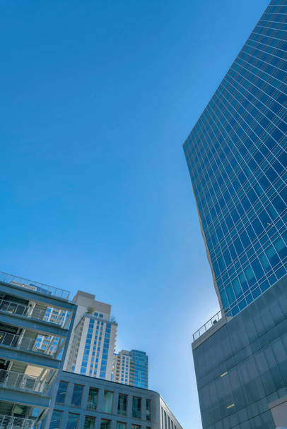 Austin, Texas- Cityscape v nízkém úhlu pohledu s moderními stavebními návrhy proti obloze. Na levé straně přes skleněnou budovu napravo je parkoviště. - Fotografie, Obrázek