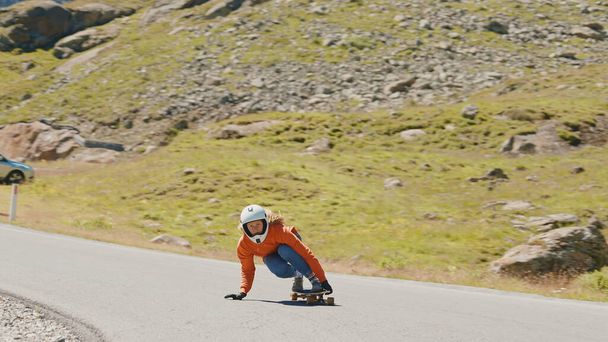 Cinematic downhill longboard session. Young woman skateboarding and making tricks between the curves on a mountain pass. Concept about extreme sports and people - Fotografie, Obrázek