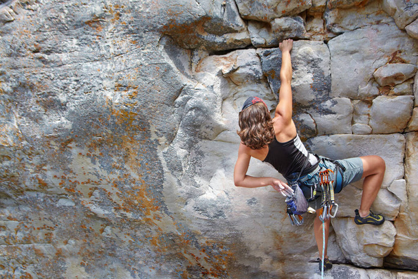 Determined to reach the top. A young rock climber scaling a mountain - copyspace - Photo, Image