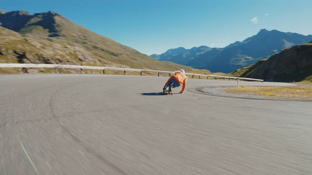 Кинематографический спуск на длинной доске. Молодая женщина катается на скейтборде и делает трюки между поворотами на горном перевале. Концепция экстремального спорта и людей - Фото, изображение